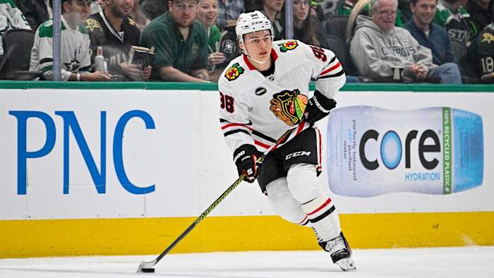 Connor Bedard handles the puck in a white Blackhawks jersey